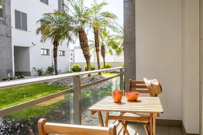 a table and chairs on a balcony with palm trees at Secret Stay Funchal by YOUR KEY in Funchal