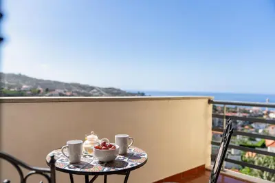 a table with two cups of coffee and fruit on a balcony at Lobos Horizon by An Island Apart in Câmara de Lobos