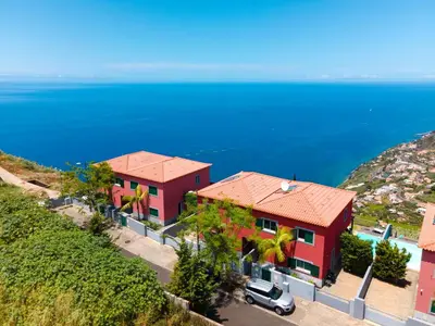 a red house on a hill next to the ocean at Villa Antonina by Madeira Real in Arco da Calheta
