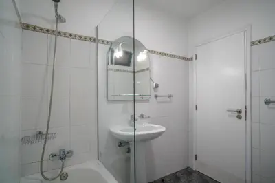 a white bathroom with a sink and a shower at Casa Giri in Relógio do Poiso