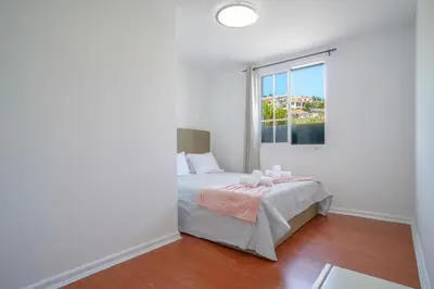 a white bedroom with a bed and a window at Casa Giri in Relógio do Poiso