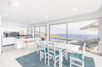 a kitchen and dining room with a view of the ocean at Villa Oceano Sereno by GALMI in Ponta do Sol