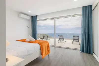 a bedroom with a bed and a view of the ocean at Villa Oceano Sereno by GALMI in Ponta do Sol