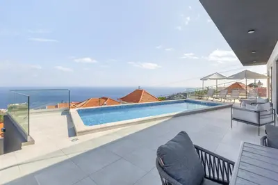 a swimming pool with a view of the ocean from a house at Villa Oceano Sereno by GALMI in Ponta do Sol
