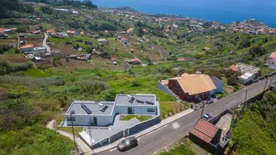 a house on a hill next to a road at CASA PANORAMA SOL- NEW VILLA WITH HEATED SALTWATER POOL and FANTASTIC SEA VIEW in Ponta do Sol