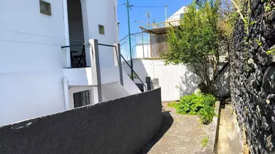 a white building with a staircase next to a wall at Consolação Sea View in Funchal