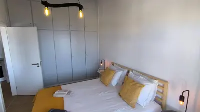 a bedroom with a bed with white sheets and yellow pillows at Consolação Sea View in Funchal