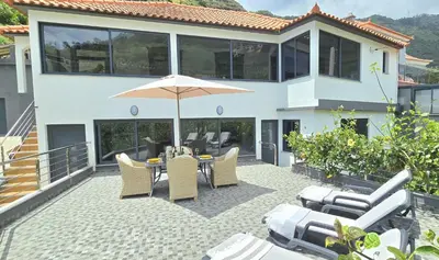 a patio with a table and chairs and an umbrella at Annamoraj by Eurostay - Nature's peace - Your cozy escape! in Ribeira Brava