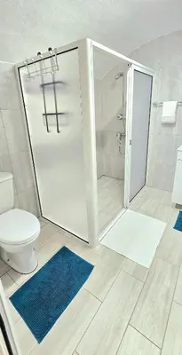 a white bathroom with a shower and a toilet at Annamoraj by Eurostay - Nature's peace - Your cozy escape! in Ribeira Brava
