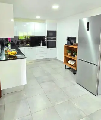 a large kitchen with white cabinets and a refrigerator at Annamoraj by Eurostay - Nature's peace - Your cozy escape! in Ribeira Brava