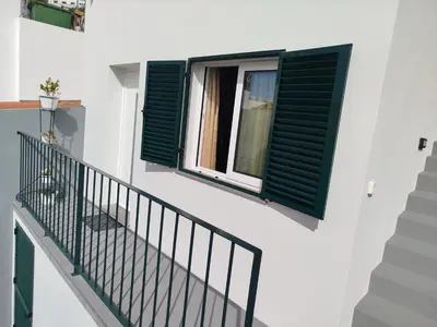 a staircase with green shutters and a window at Baía dos Lobos in Câmara de Lobos
