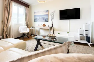 a living room with a white couch and a table at Ocean & Mountain Views-Garage Parking-Walk to Praia do Vigário in Câmara de Lobos