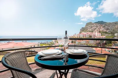 a table and chairs on a balcony with a view at Ocean & Mountain Views-Garage Parking-Walk to Praia do Vigário in Câmara de Lobos