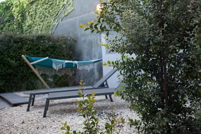 a blue bench with a hammock in a garden at The Jolie - A Retreat in the City in an Entire House in Funchal