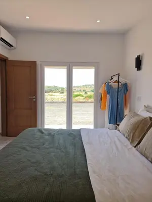 a bedroom with a large bed and a sliding glass door at Novo! Jacuzzi, campo e praia in Vila do Bispo