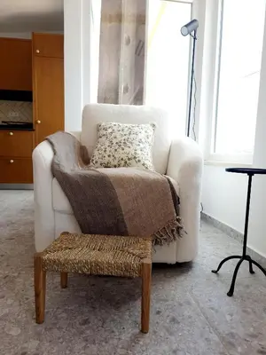 a living room with a chair with a blanket at Novo! Jacuzzi, campo e praia in Vila do Bispo