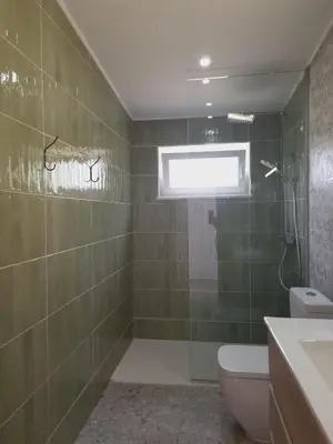 a bathroom with a shower and a toilet and a window at Novo! Jacuzzi, campo e praia in Vila do Bispo
