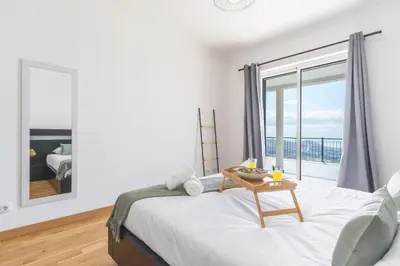a bedroom with a bed with a table and a window at Palm Paradise Villa by AH in Câmara de Lobos