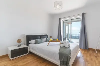 a bedroom with a bed with a table and a large window at Palm Paradise Villa by AH in Câmara de Lobos
