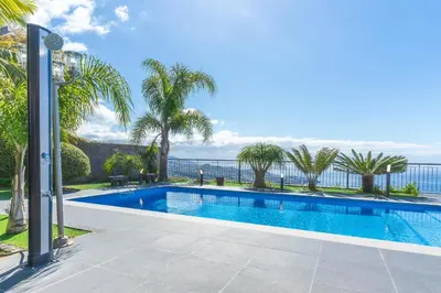 a swimming pool with the ocean in the background at Palm Paradise Villa by AH in Câmara de Lobos