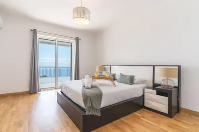 a bedroom with a large bed and a large window at Palm Paradise Villa by AH in Câmara de Lobos
