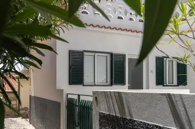 a white house with green shutters and a fence at Barlavento by An Island Apart in Porto Santo