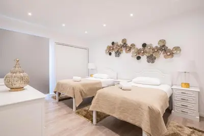 a white bedroom with two beds and a chandelier at Piornais Apartment by Holiday Rental Madeira in Funchal
