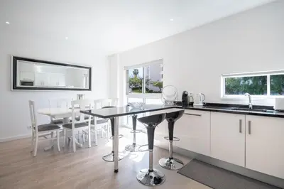 a kitchen with white cabinets and a table with chairs at Piornais Apartment by Holiday Rental Madeira in Funchal
