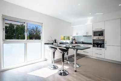 a kitchen with white cabinets and a large window at Piornais Apartment by Holiday Rental Madeira in Funchal