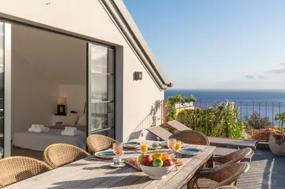 a dining table on a balcony with a view of the ocean at Eden Funchal by LovelyStay in Funchal