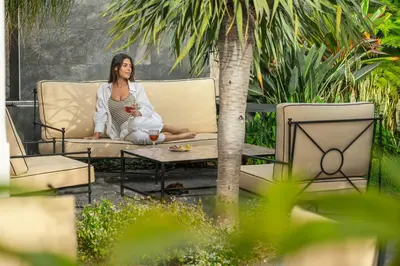 a woman sitting on a couch in a garden at Eden Funchal by LovelyStay in Funchal