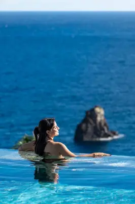 a woman sitting in the water in the ocean at Savoy Monumentalis IV by An Island Apart in Funchal