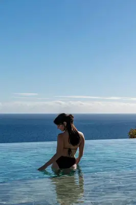 a woman sitting in the water in a swimming pool at Savoy Monumentalis IV by An Island Apart in Funchal