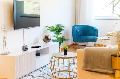 a living room with a tv and a blue chair at GuestReady - O Cantinho dos Pestanas in Caniço