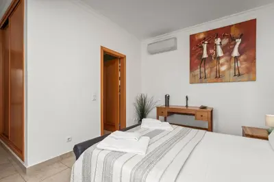 a white bedroom with a bed and a painting on the wall at Coastal Terrace Apartment in Lagos