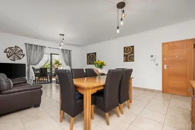 a dining room with a wooden table and black chairs at Coastal Terrace Apartment in Lagos