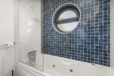 a blue tiled bathroom with a mirror and a tub at Coastal Charm Apartment in Lagos