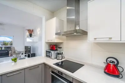 a kitchen with white cabinets and a red tea kettle at Blue Horizon Apartment in Luz