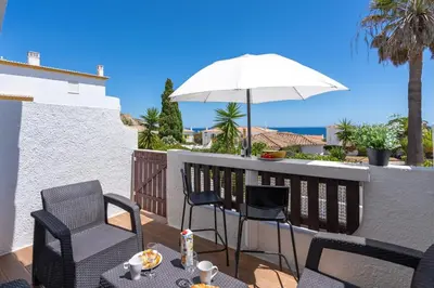 a patio with chairs and an umbrella on a balcony at Blue Horizon Apartment in Luz
