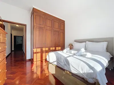 a bedroom with a large bed and a wooden cabinet at Villa Santa Luzia 2 by Atlantic Holiday in Santa Luzia