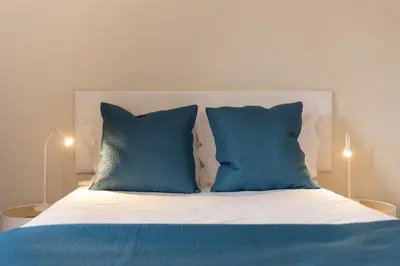 a bed with two blue pillows on top of it at Olimpo I by An Island Apart in Funchal