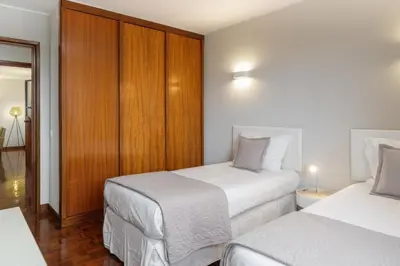 a bedroom with two beds and a wooden cabinet at Olimpo I by An Island Apart in Funchal