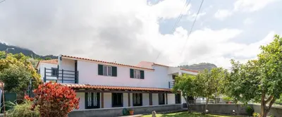 a large white house with mountains in the background at Casa Santos- Arco da Calheta in Arco da Calheta