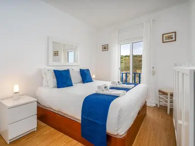 a bedroom with a large bed with blue pillows at Retreat with sea view #1972 in Budens