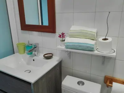 a bathroom with a sink and a toilet and a mirror at Adega Studio in Machico