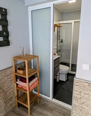 a bathroom with a toilet and a shelf with towels at Adega Studio in Machico