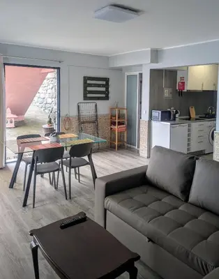 a living room with a couch and a table and a kitchen at Adega Studio in Machico