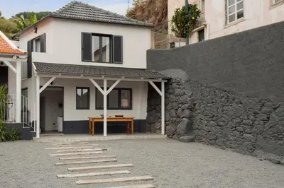 a white house with a stone wall and a table at The Village Loft in Caniço