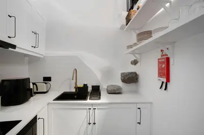 a white kitchen with a sink and a stove at The Village Loft in Caniço