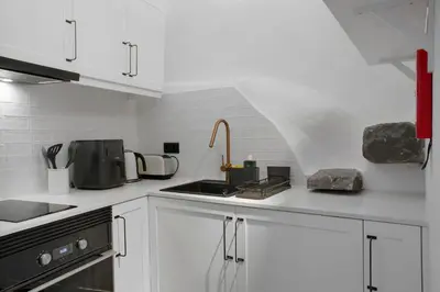 a white kitchen with a sink and a stove at The Village Loft in Caniço